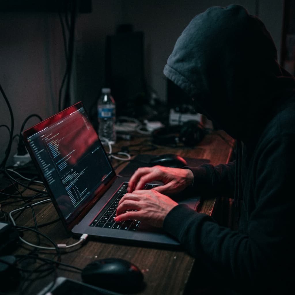 The Threat Axis: Unseen Competitors and Ex-Employees A dark cinematic shot of an anonymous figure aggressively typing on a laptop launching a digital review attack