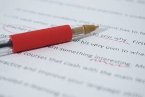 Red pen correcting proofs on paper